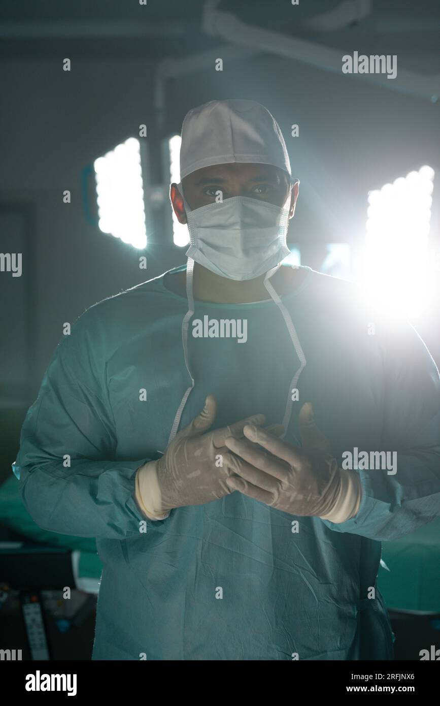Portrait of biracial male surgeon wearing surgical gown in operating theatre at hospital Stock Photo