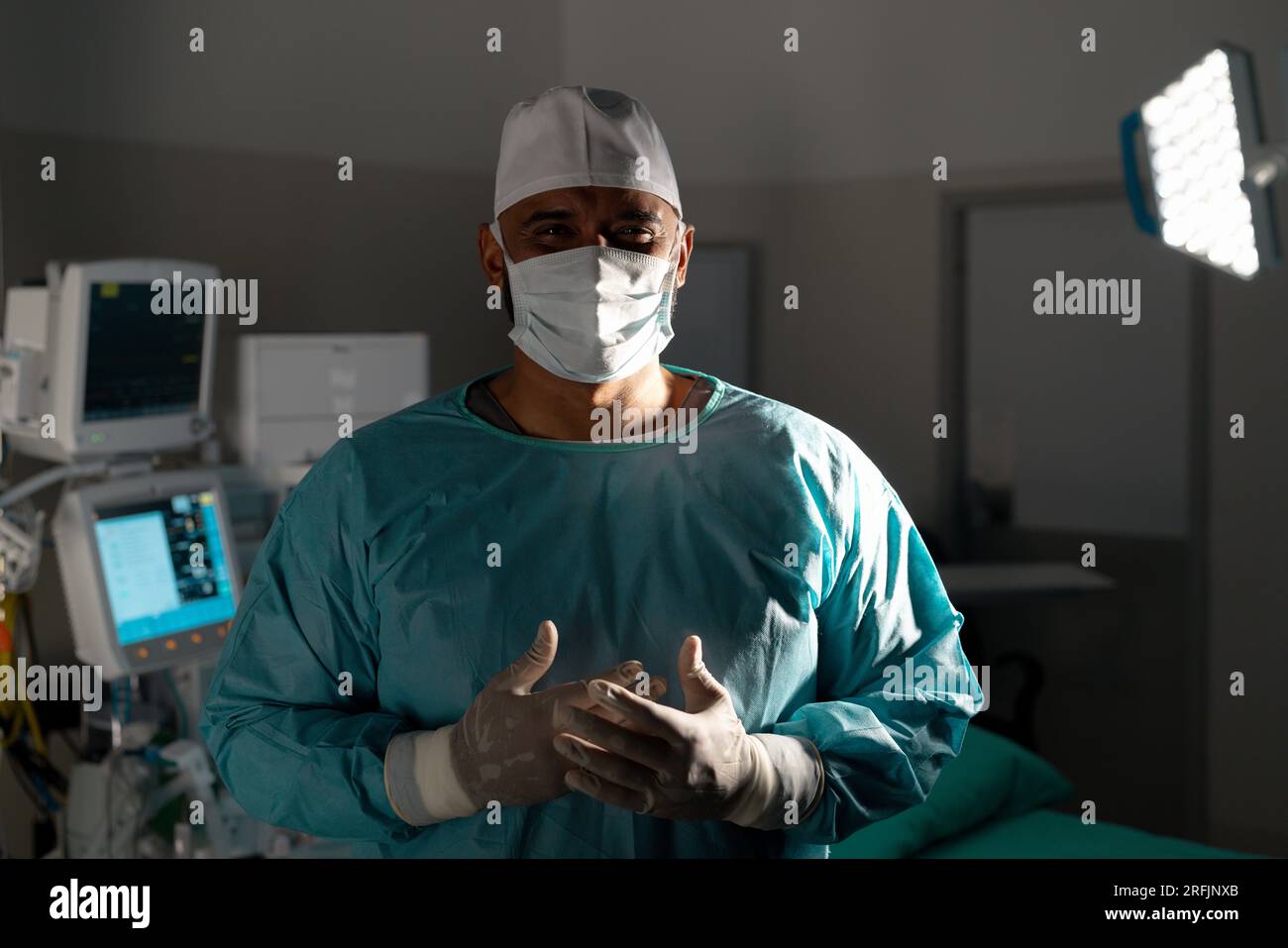 Portrait of biracial male surgeon wearing surgical gown in operating ...