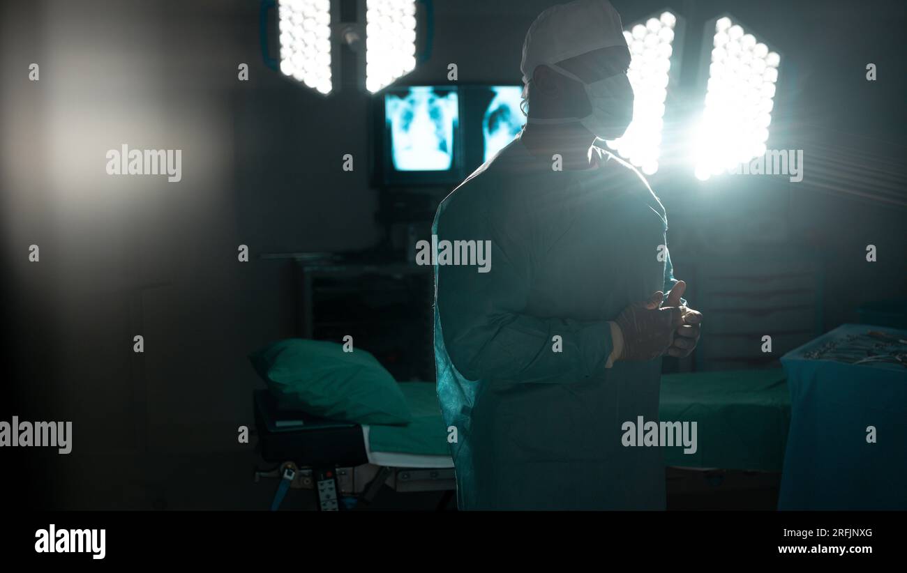 Biracial male surgeon wearing surgical gown and face mask in operating ...