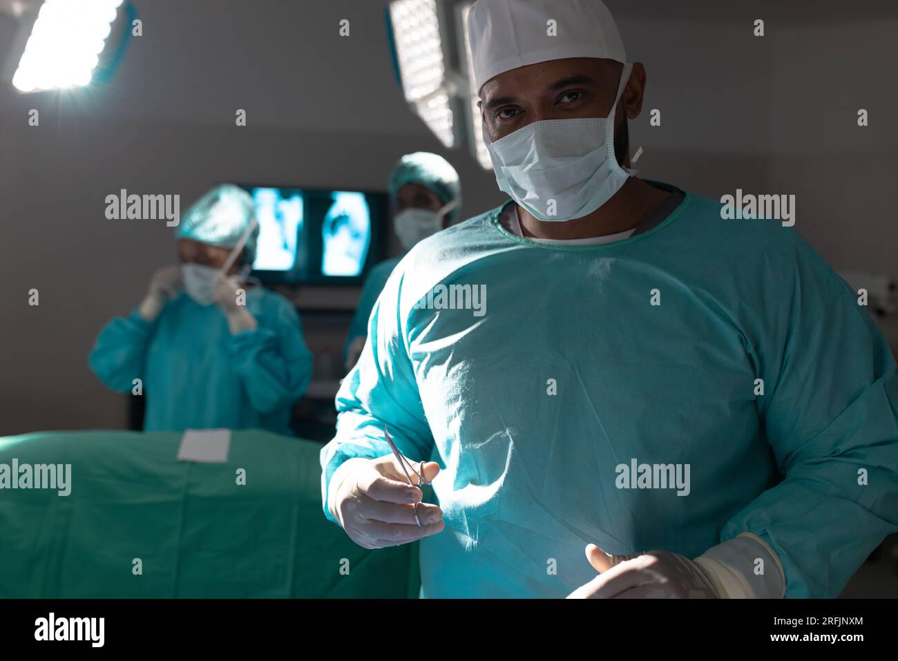 Portrait of biracial male surgeon wearing surgical gown in operating theatre at hospital Stock Photo