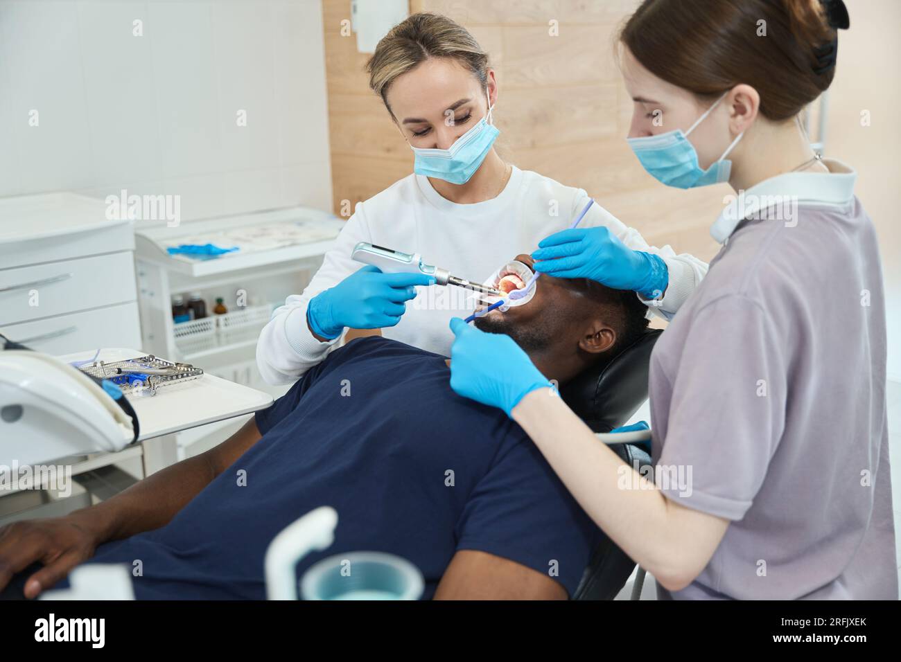 Nurse holding saliva ejector while dentist using oral anesthesia