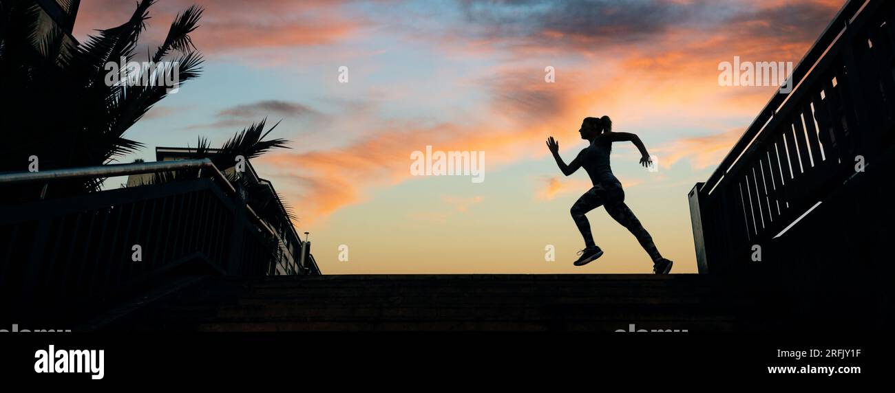 Unrecognizable young female runner silhouette running over an urban background with palm trees and cloudy sunset sky Stock Photo