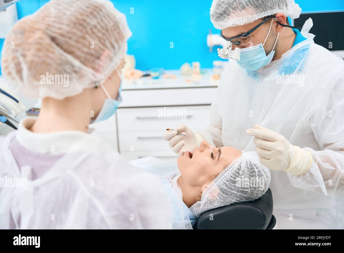 Dentist seals the tooth canal to young woman under microscope Stock