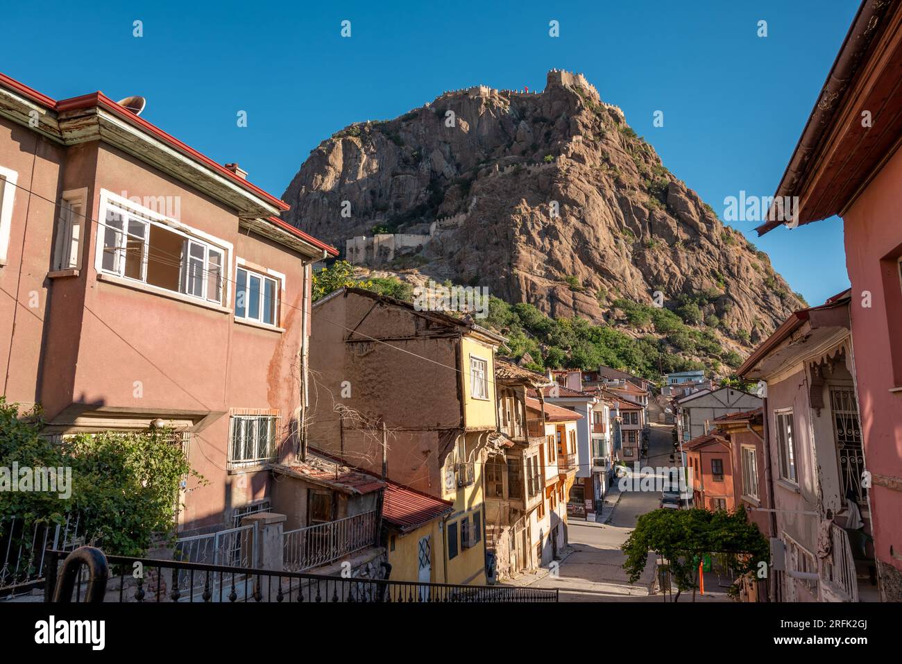 Traditional Turkish Ottoman houses in Afyonkarahisar Turkey. Afyon Castle on the rock and Mevlevihane Museum in front of it Stock Photo