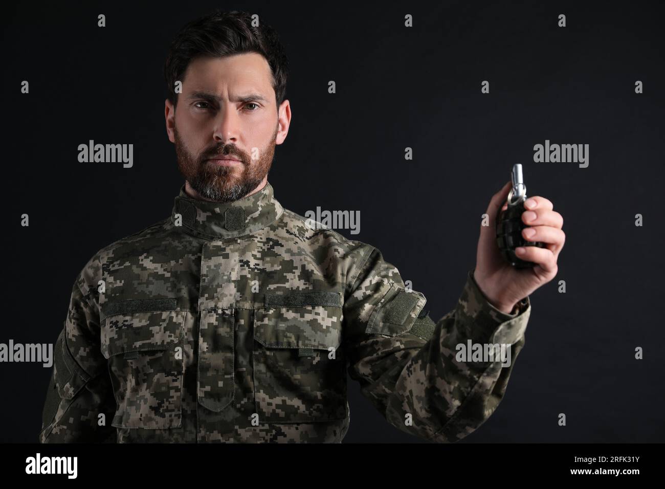 Soldier holding hand grenade on black background. Military service