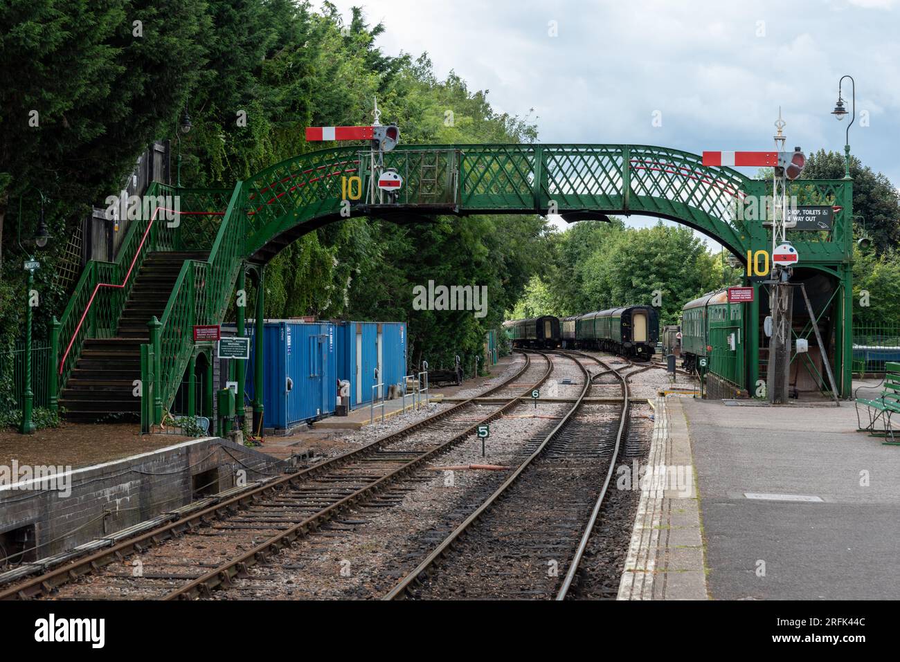 Empty platform and bridge at Alresford train station with carriages in the distance. Part of the Watercress line in Hampshire, England. August 2023 Stock Photo