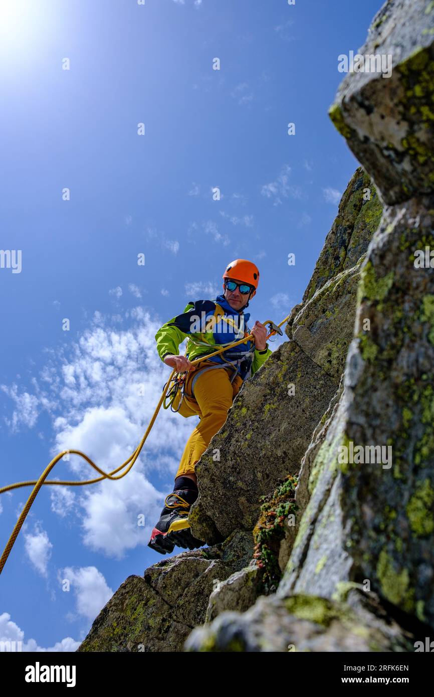 Man alpinist rappelling on steep rock in Swiss Alps Stock Photo