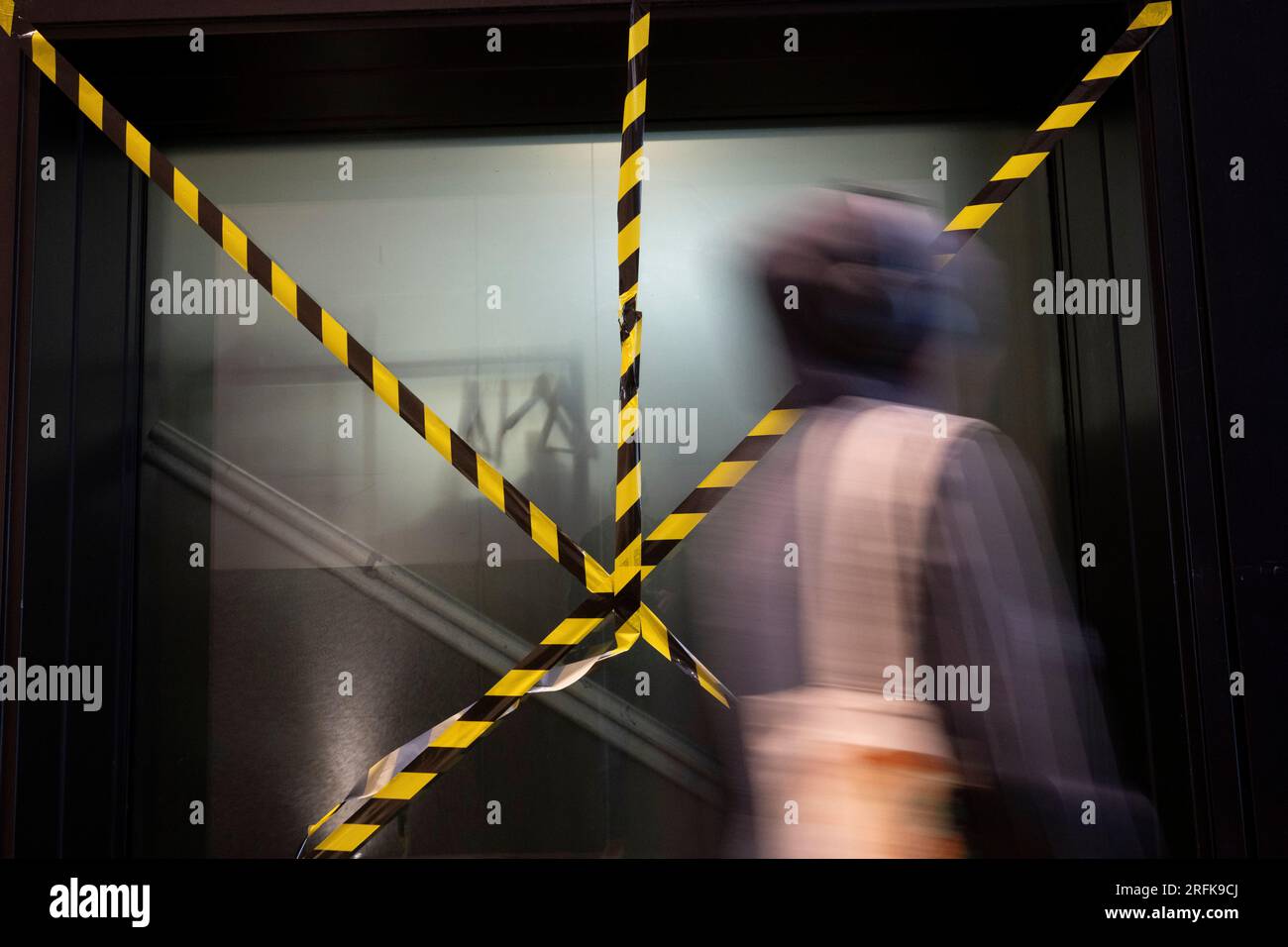 A City worker walks past criss-crossed hazard tape in the City of London, the capital's financial district, on 3rd August 2023, in London, England. Stock Photo
