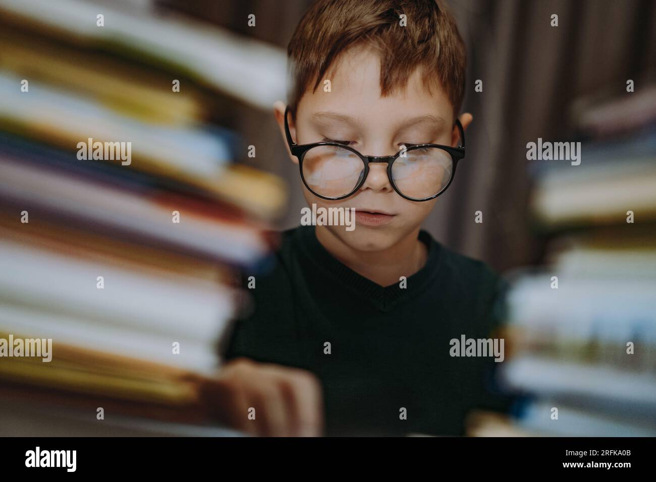 cute caucasian boy wearing glasses covering head with book. Cheerful
