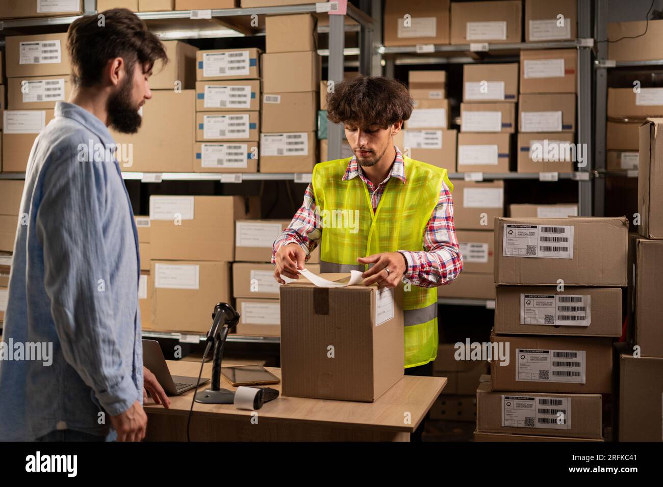 Post office worker sticking barcode on parcel at counter indoors