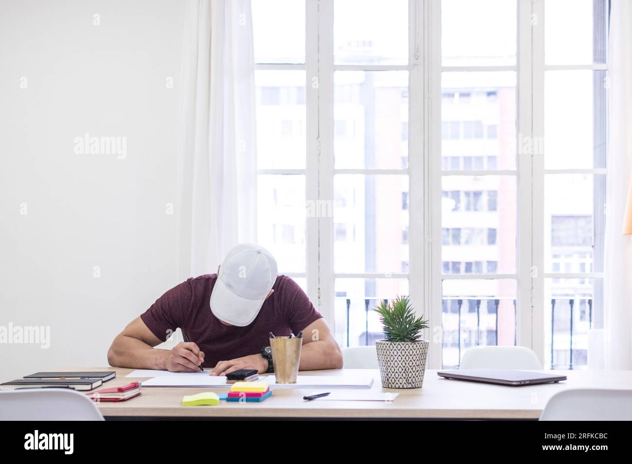 Young man with a cap, working on a table Stock Photo