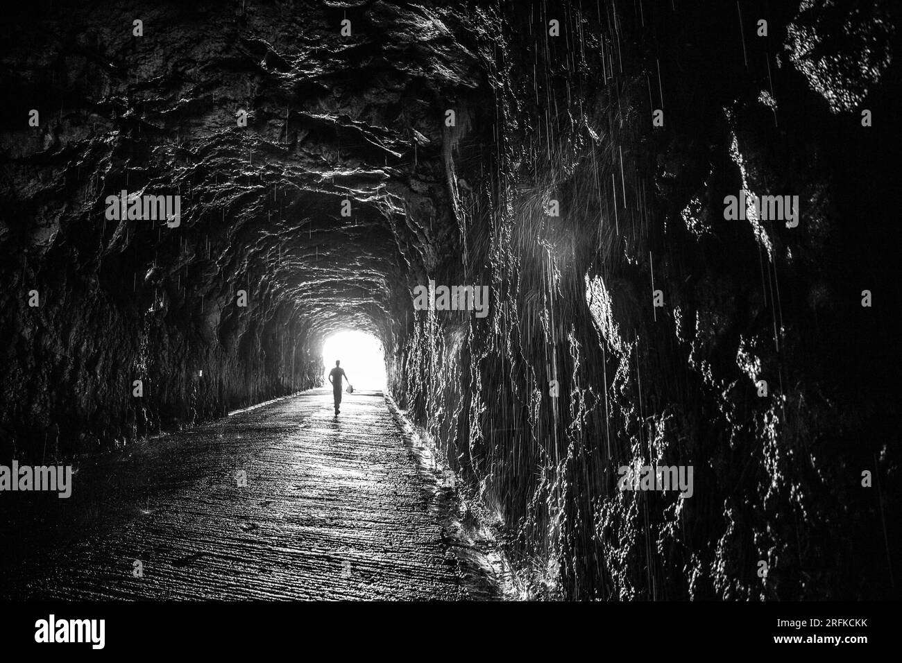 Black and white photo of the person walking inside the tunnel Stock Photo