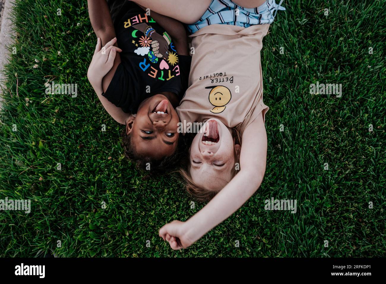 Two girls making goofy faces in grass Stock Photo