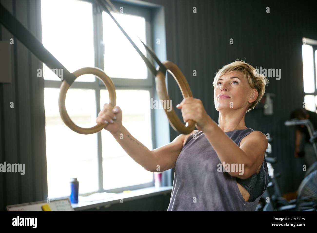 Mature woman training in gym, doing exercises with gymnastics rings