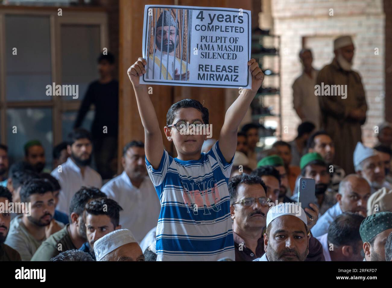 A Kashmiri boy holds a placard with the photograph of separatist leader ...