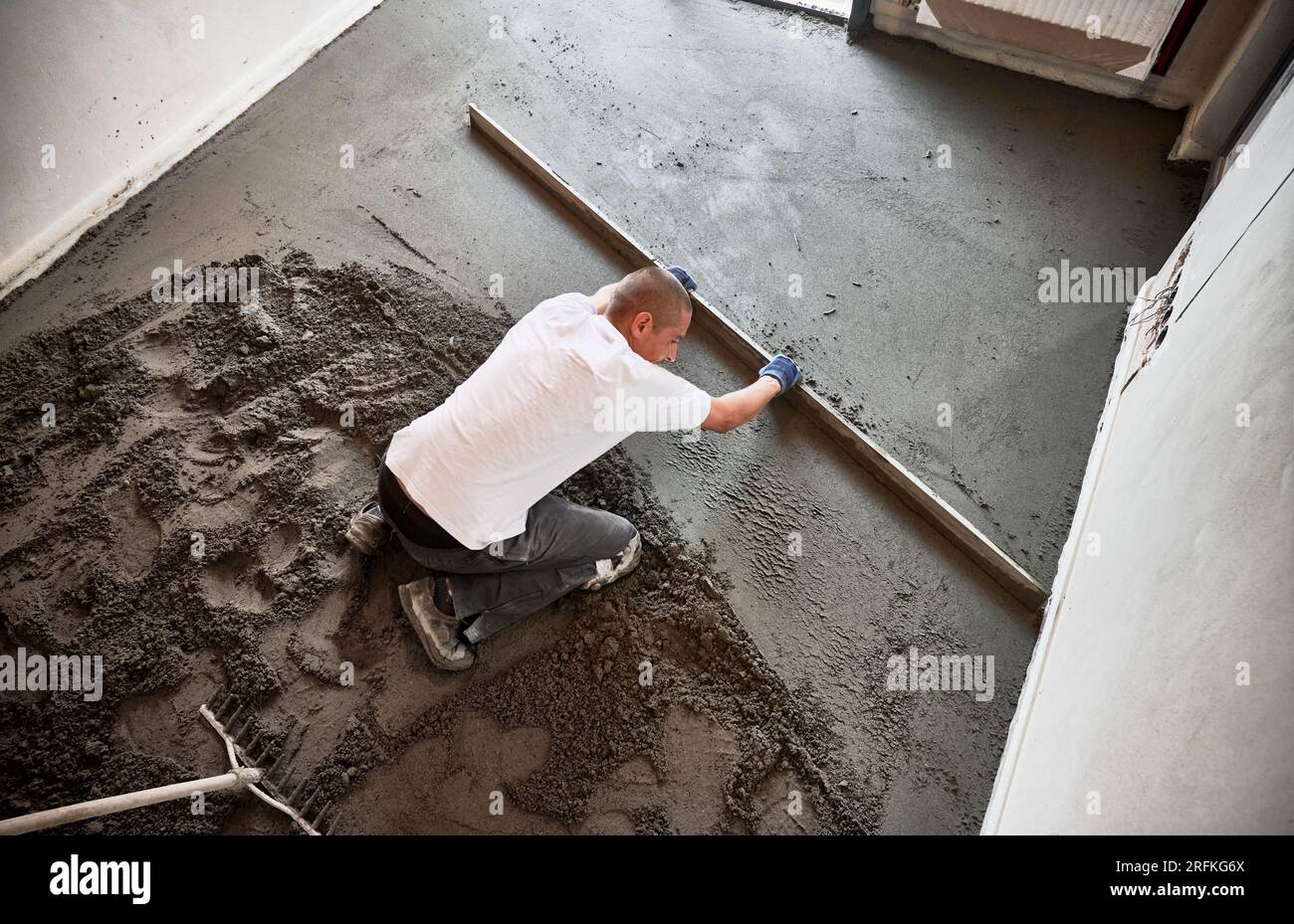 Man smoothing and leveling surface with straight edge while screeding