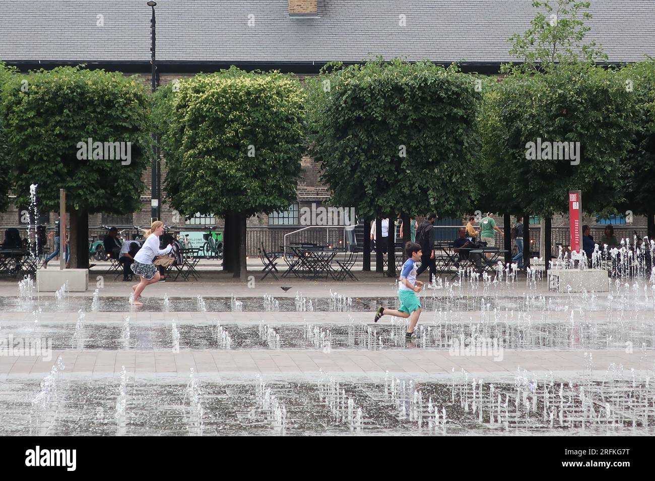 Young children enjoy running through the dancing fountains and water jets in Granary Square, the heart of the redeveloped King's Cross, London. Stock Photo