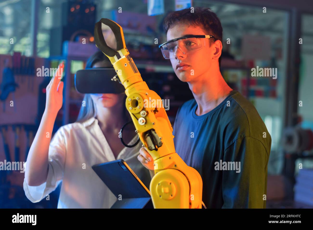 Teens doing experiments in robotics in a laboratory. Boy in protective ...