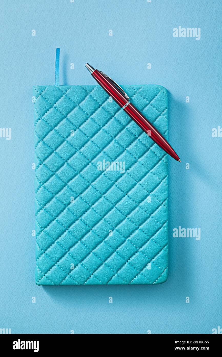 Blue Notepad And Red Ballpoint Pen On Blue Background Stock Photo