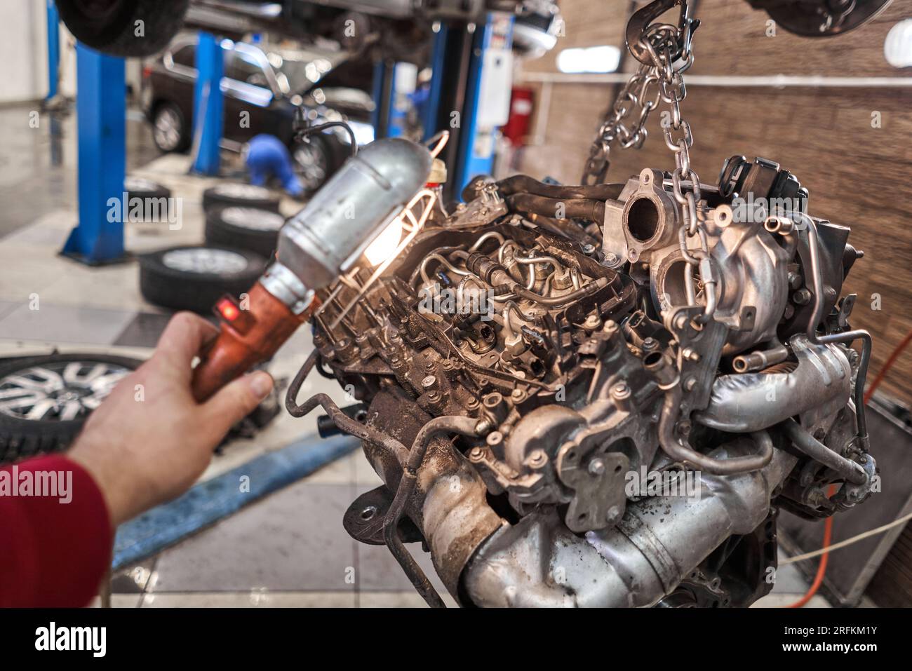 A car mechanic inspects the engine with a flashlight. Engine Block on a
