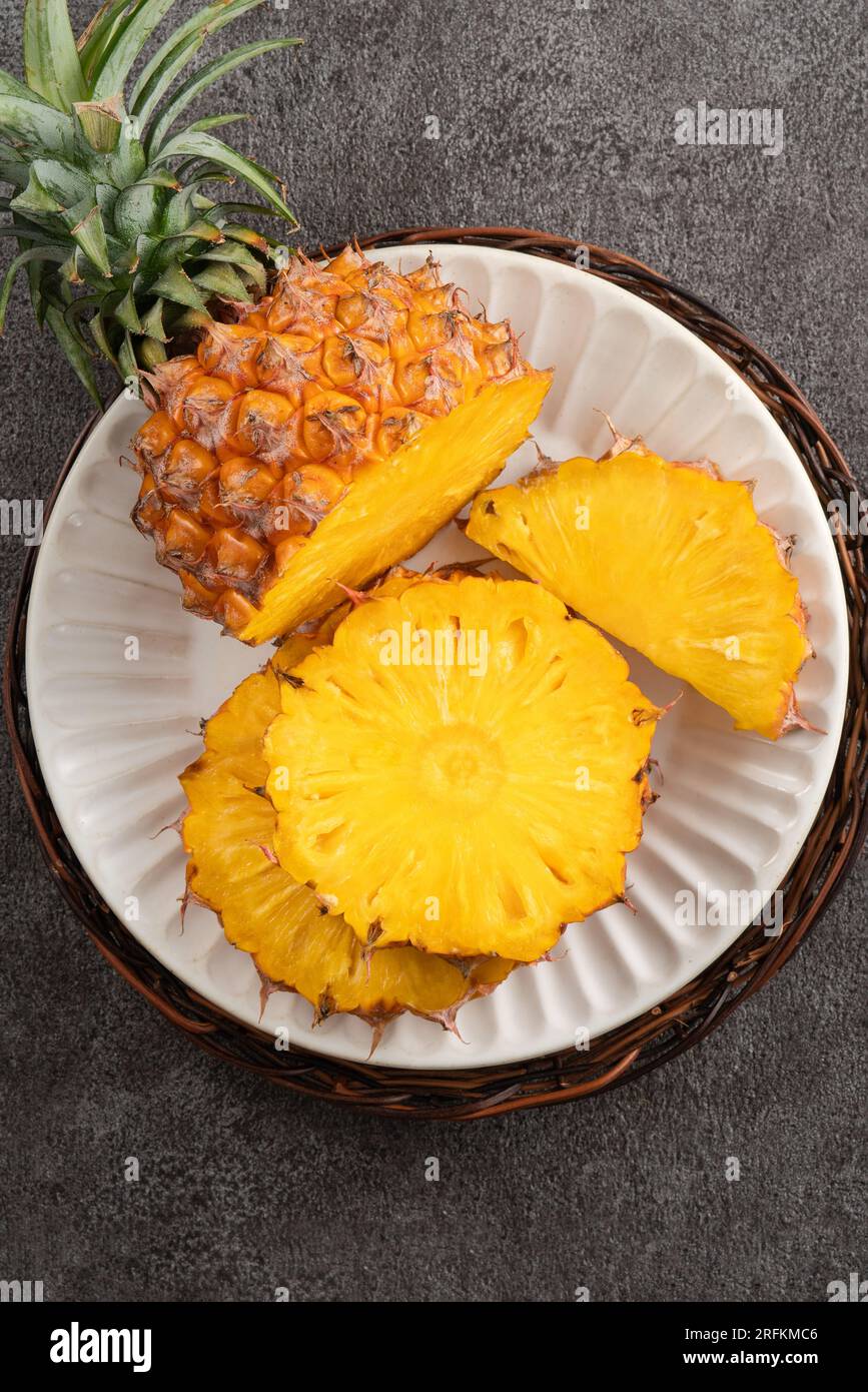 Top view of fresh cut pineapple with tropical leaves on gray table background. Stock Photo