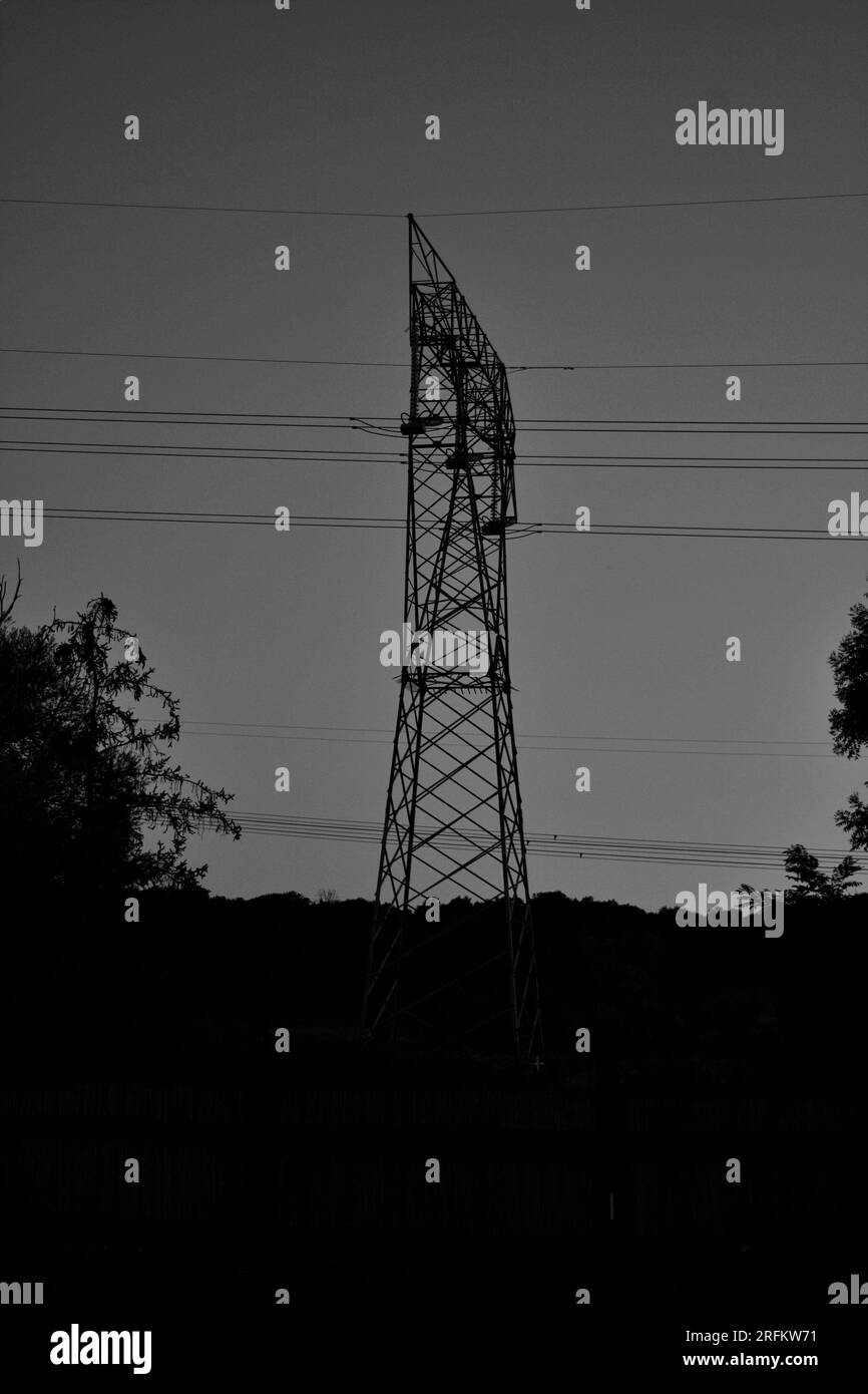 Boldly outlined against the sky, the silhouette of an electrical pylon makes a striking focal point. A minimalist marvel of modern infrastructure. Stock Photo