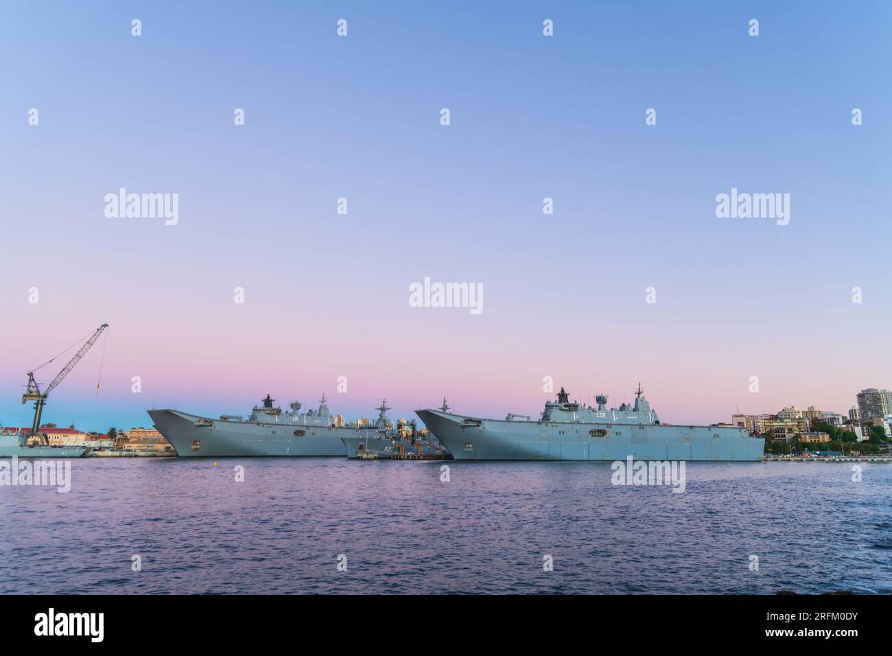 Sydney, NSW, Australia - April 20, 2022: HMAS Adelaide (L01) and HMAS Canberra (L02) Canberra-class landing helicopter dock ships docked in Sydney Har Stock Photo