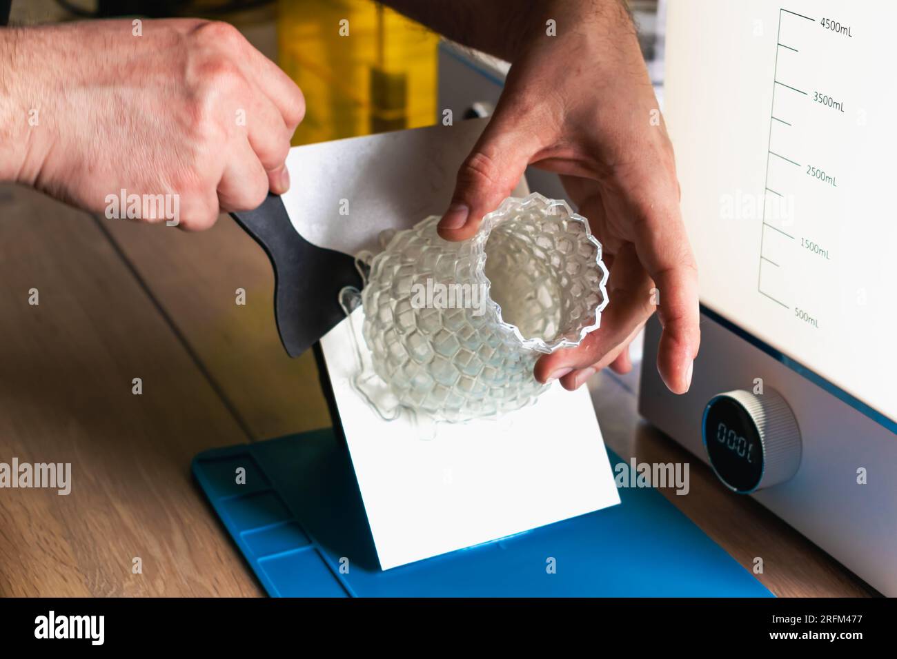 Man holding a 3d resin object with next to him wash and cure machines ...