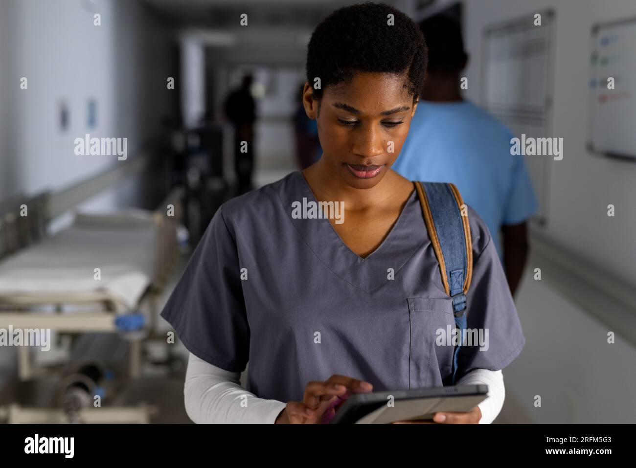 African american female doctor using tablet in corridor at hospital Stock Photo