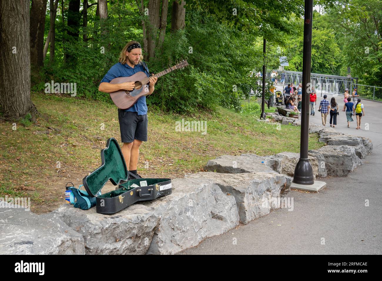 Niagara Falls, NY - July 31, 2022: Busker playing guitar on Goat Island just beyond the bridge. Stock Photo
