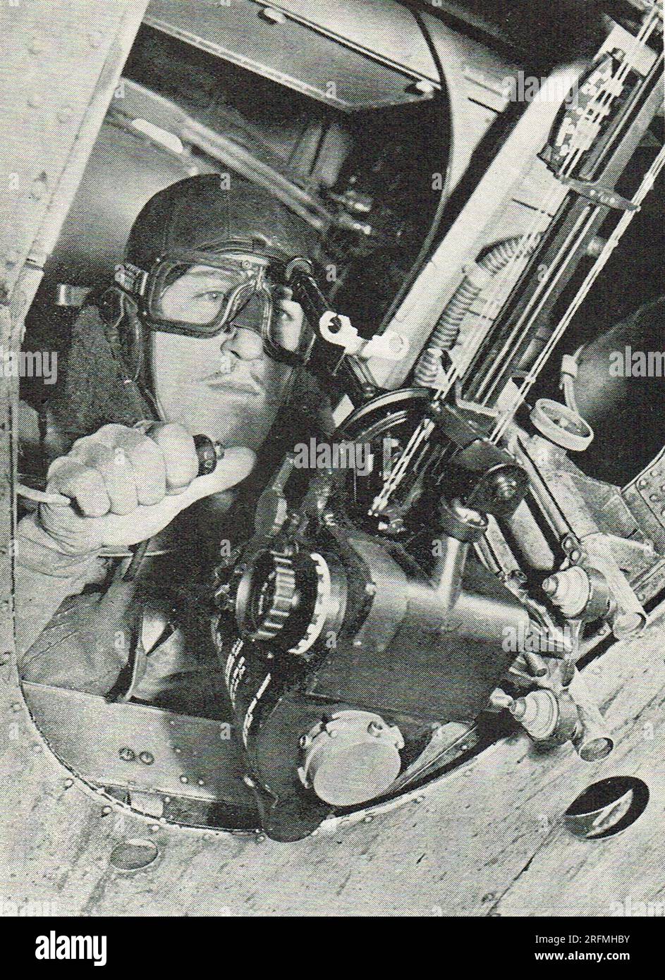 Bomb aimer taking aim during world war 2. The navigator is holding  the bomb release switch in his right hand. Stock Photo
