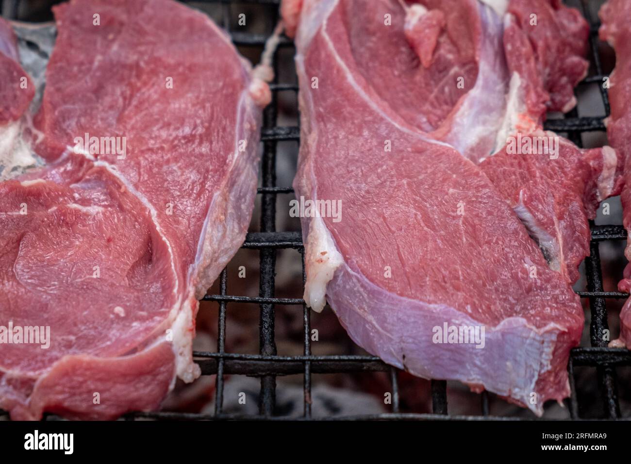 raw beef pieces prepared for grilling on a charcoal grill Stock Photo