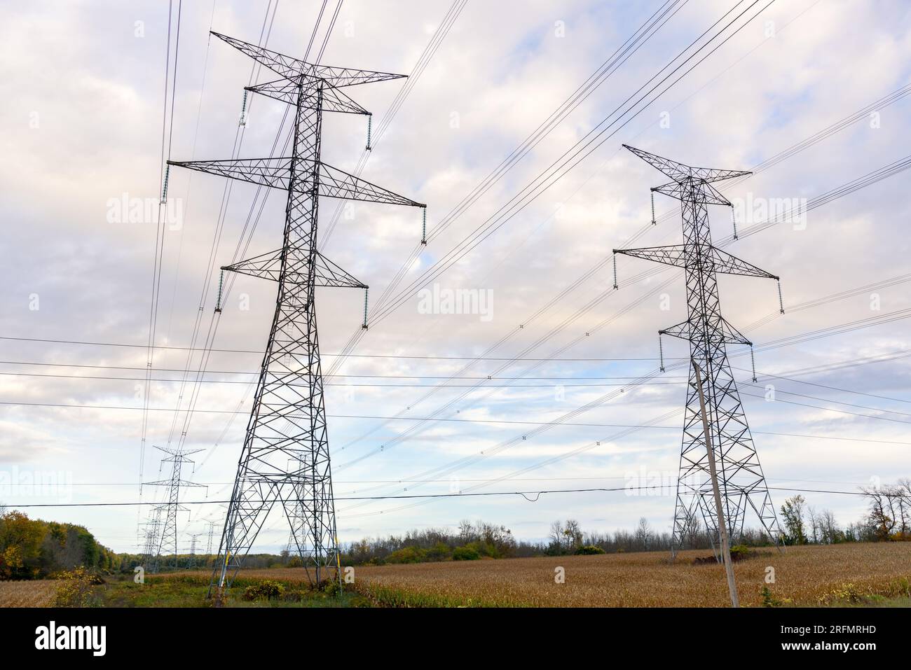 Tall pylons supporting high voltage lines over farmland on a cloudy autumn day Stock Photo
