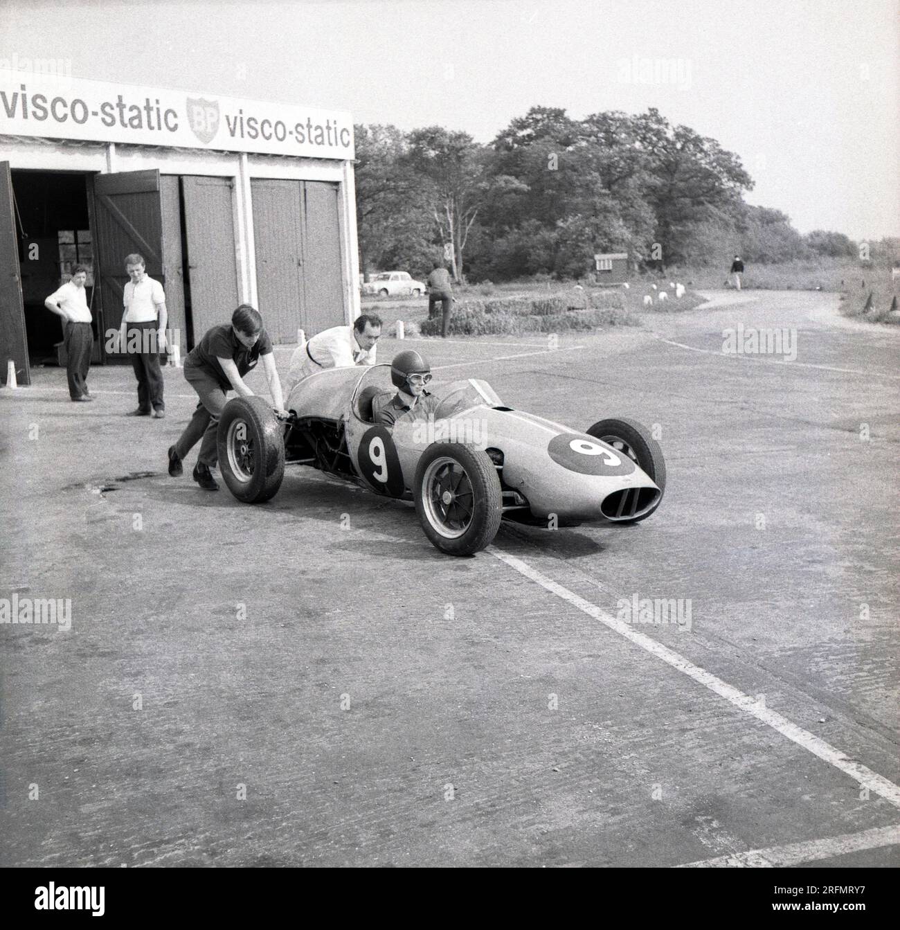 1962, historical, a young male driver sitting in a single-seater Cooper motor racing car being pushed onto the circuit at the motor racing drivers school at the Finmere Aerodrome, Bucks, England, UK, Stock Photo