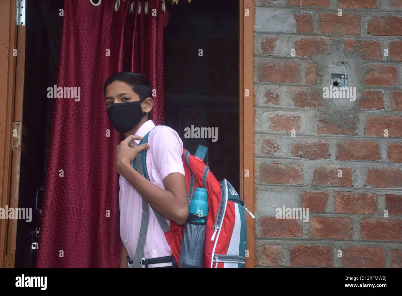 teen student boy wearing school uniform and face mask going to school with bag pack in corona virus pandemic, selective focus Stock Photo