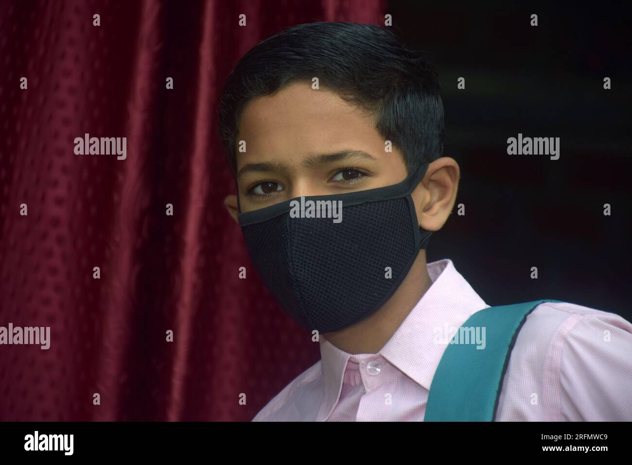 teen student boy wearing school uniform and face mask going to school with bag pack in corona virus pandemic Stock Photo