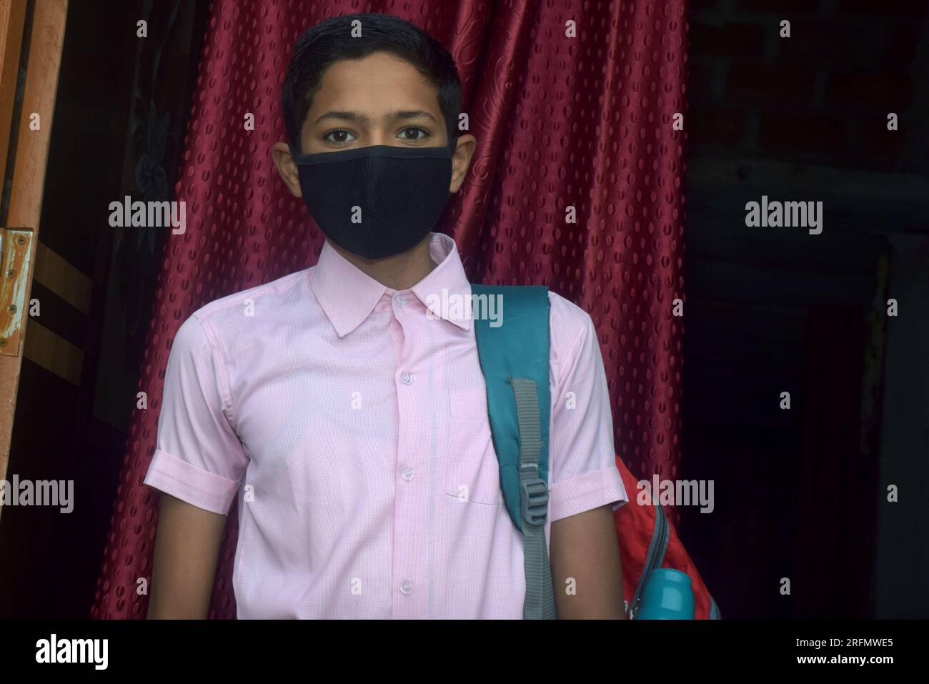 teen student boy wearing school uniform and face mask going to school with bag pack in corona virus pandemic, selective focus Stock Photo