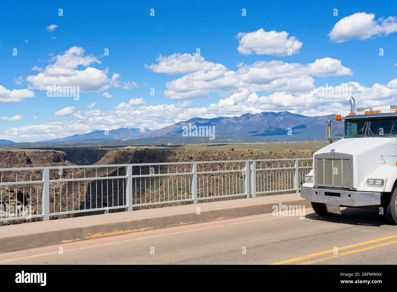 White truck crossing Rio Grande Gorge Bridge 650 feet above Rio Grande Gorge on US 64 with Sangre de Cristo Mountains on horizon. Stock Photo