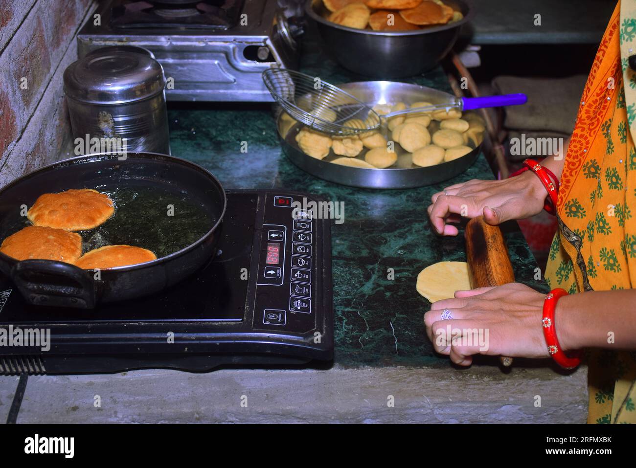 modern black induction stove, Woman standing in kitchen cooking food