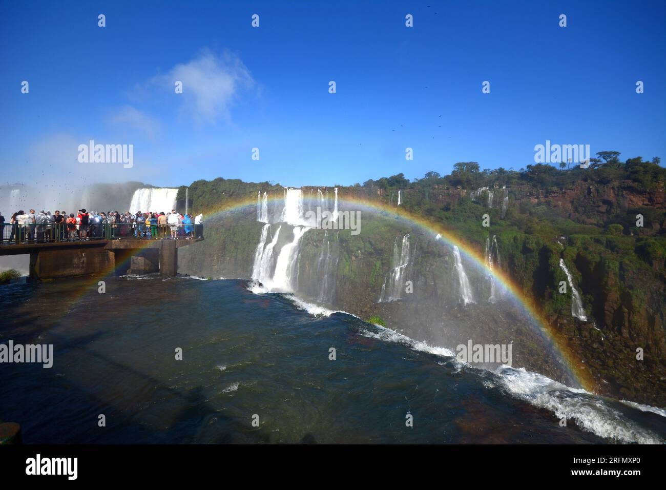 Tourists at Iguazu Falls, one of the great natural wonders of the world, on the border of Brazil and Argentina. Rainbow in the foreground Stock Photo