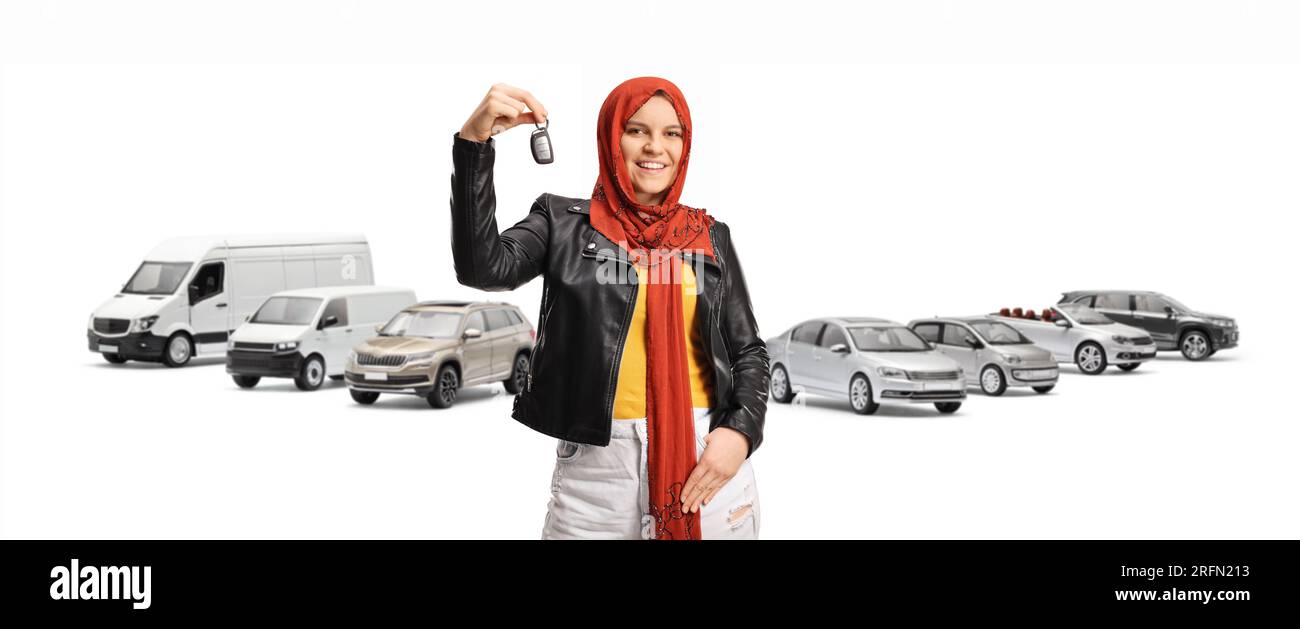 Young muslim woman with a hijab holding car keys and smiling in front of parked vehicles isolated on white background Stock Photo