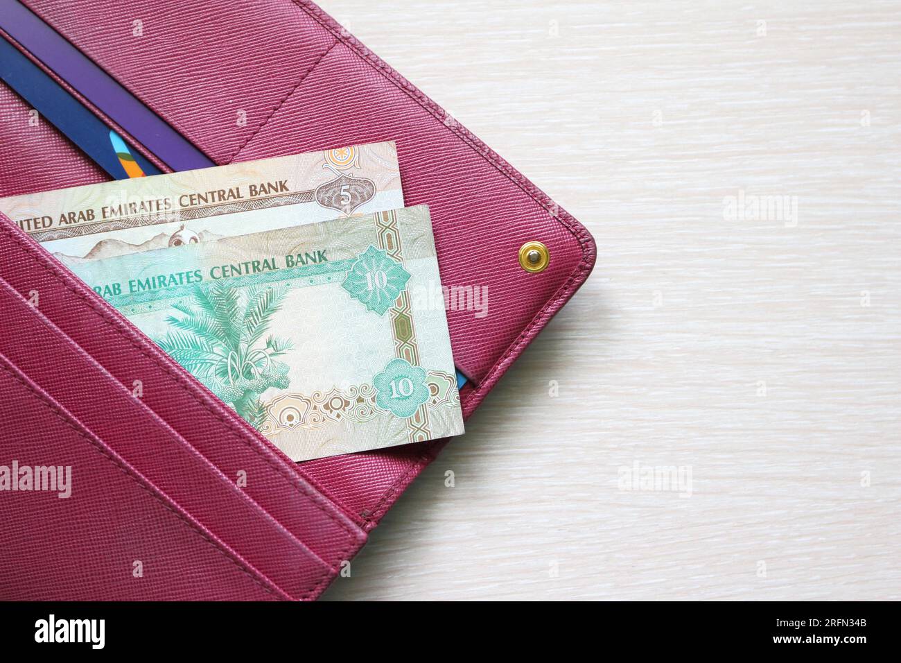 UAE dirham bills in a leather wallet. Fucsia red wallet, purse. Banknotes. Money in cash. Fan of bills. The currency of United Arab Emirates. AED Stock Photo