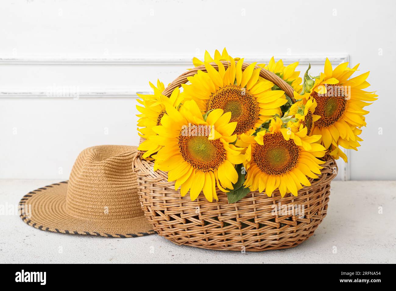 Wicker basket with sunflowers and straw hat on white background Stock ...