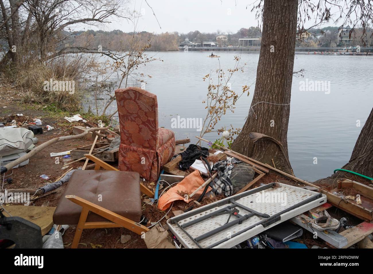 Austin Texas USA, January 2 2023: Trash and belongings from a long-time homeless camp line the north shore of Lady Bird Lake near Rainey Street in downtown Austin. City officials are struggling with homelessness issues along the popular hike and bike trails on public parkland that ring the lake. ©Bob Daemmrich Stock Photo