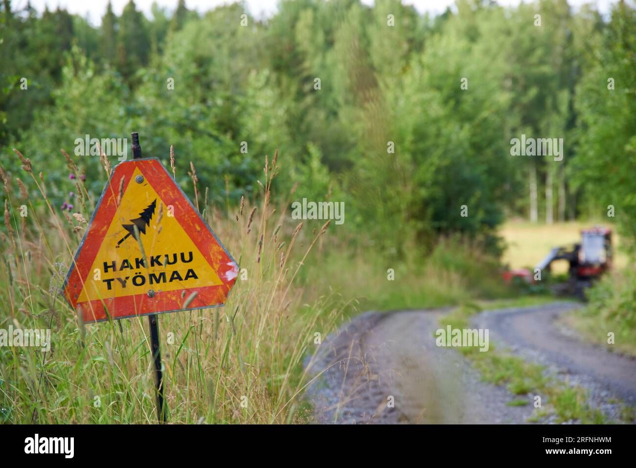 Nokia, Finland - July 31, 2023:  Woodworking site warning sign and forestry machinery on sunny July evening in Western Finland. Stock Photo