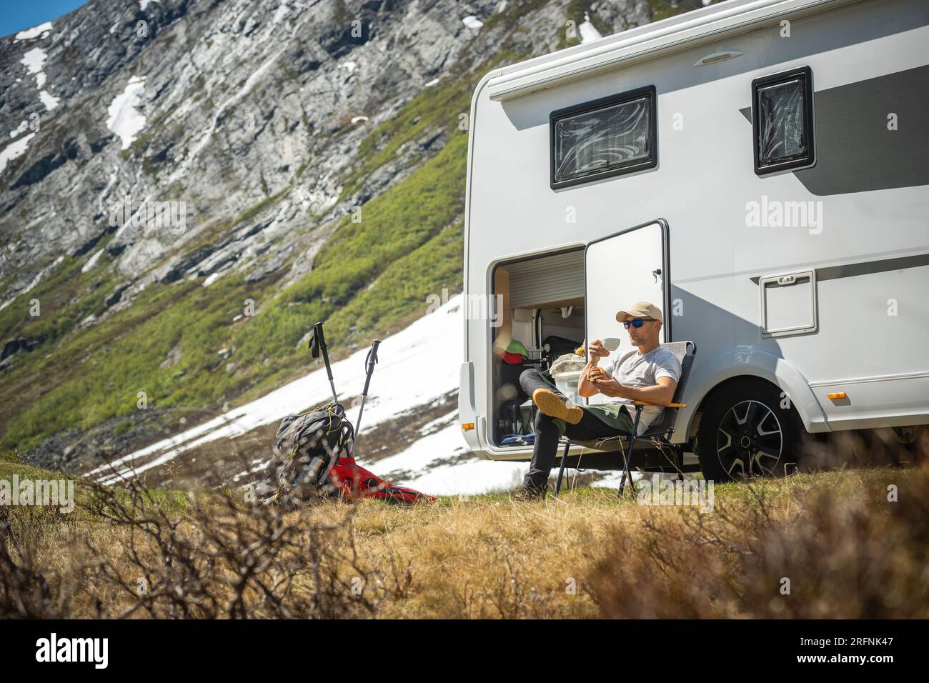 Tourist in Front of His Motor Home Taking Short Break to Eat Some Food on Fresh Air Stock Photo