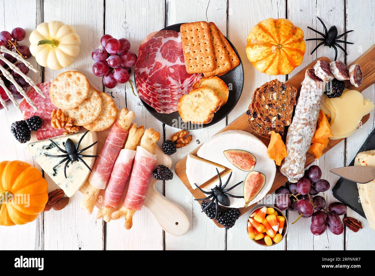 Halloween charcuterie table scene against a white wood background. Selection of cheese and meat appetizers. Top view. Stock Photo