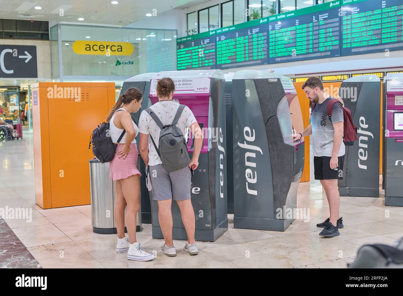 04.08.2023. Barcelona, Spain, young people getting their middle distance tickets through the vending machine with one of them having problems Stock Photo