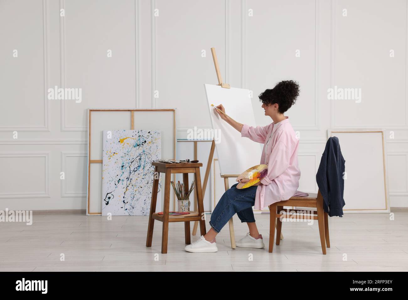 Young woman painting on easel with canvas in studio Stock Photo - Alamy