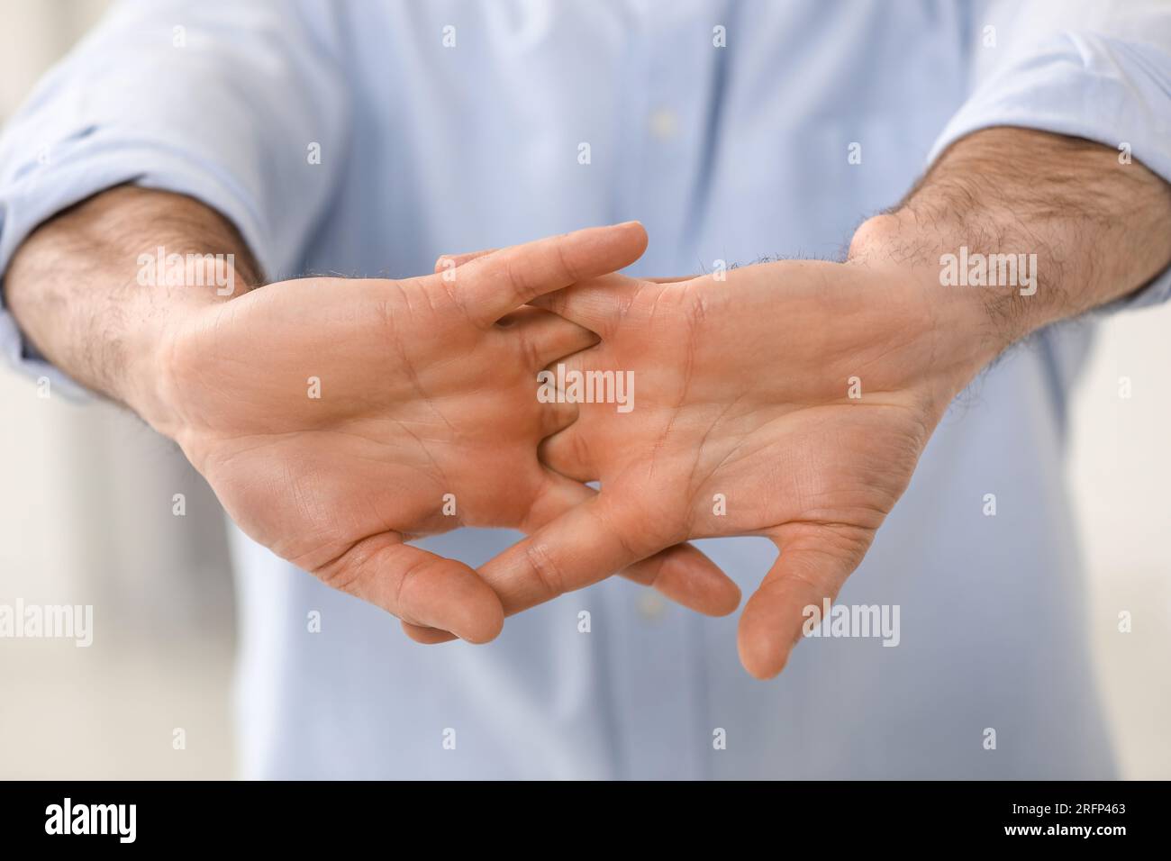 Man cracking his knuckles on blurred background, closeup. Bad habit